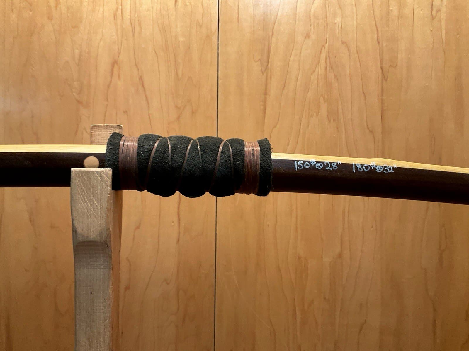 The deer skin and sinew handle wrap of the 150-pound bamboo-backed ipe warbow, its draw weights pencilled on the limb