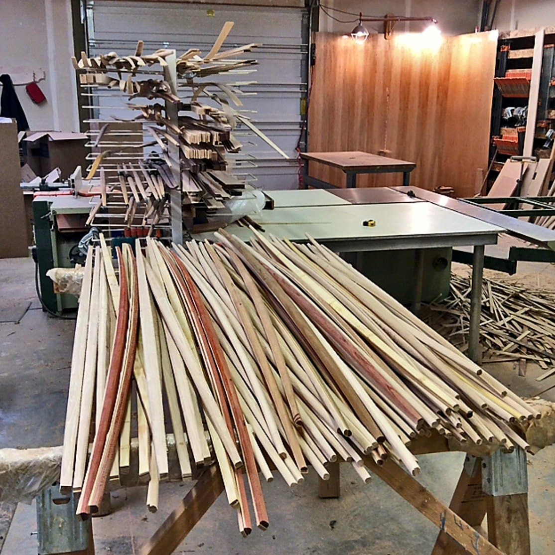 A stack of long bow blanks laid across sawhorses in Doug's workshop